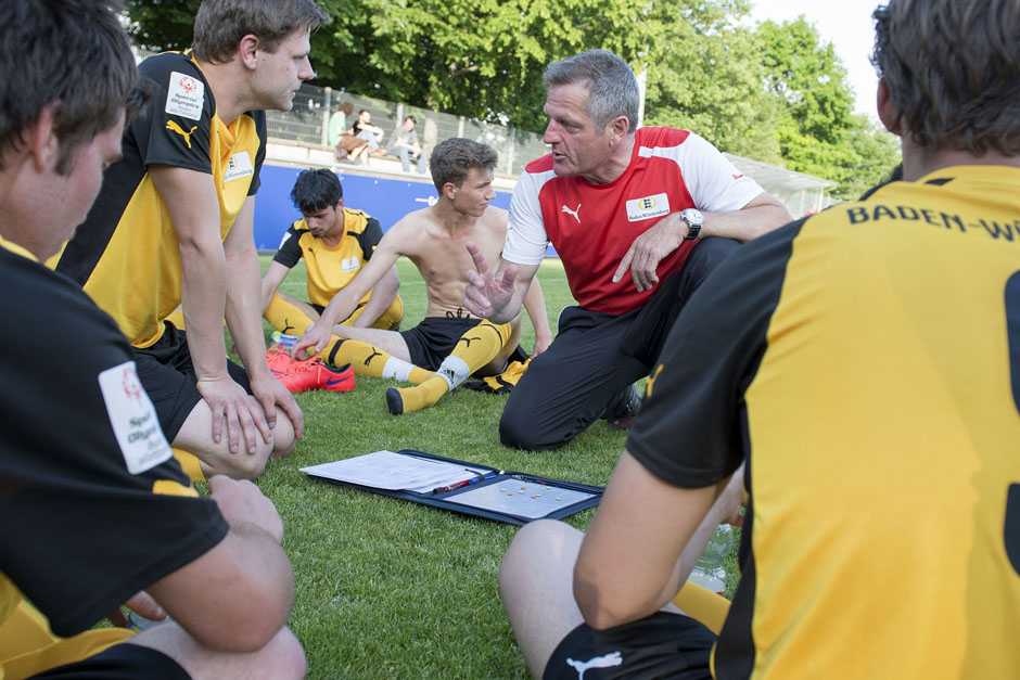 Der Trainer nutzt die Halbzeit für taktische Anweisungen. Die Mannschaft ist platt.