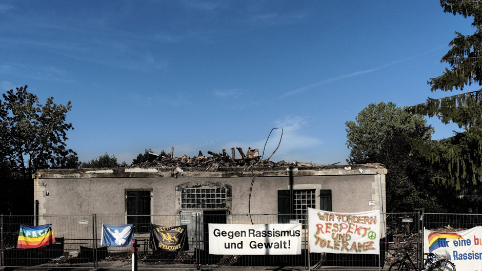 Im August fällt in Weissach im Tal ein für Flüchtlinge vorgesehenes Haus den Flammen zum Opfer. Vor der Brandruine zeigen die Dorfbewohner Flagge. Foto: Martin Storz