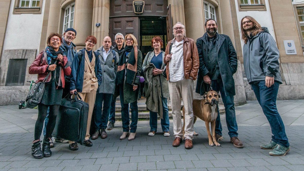 Vor dem Landgericht Frankfurt (von links): Kontext-Vorstand Anni Endress, Unterstützer Klaus Schäffer, die Anwält:innen Anja Niederhofer und Markus Köhler, Kontext-Vorstand Jürgen Klose, aus der Kontext-Redaktion Susanne Stiefel, Anna Hunger und Josef-Otto Freudenreich, Unterstützer Steffen Braun mit Hund Clyde und Kontext-Redakteur Minh Schredle. Foto: Jens Volle