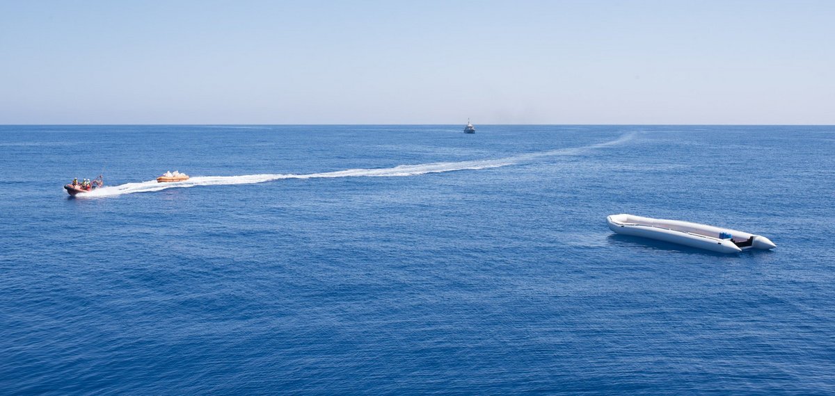 24. Mai 2018, Rettung in letzter Sekunde: Die Crew der Sea-Watch 3 (eines der schnellen Rettungsboote links) bringt 157 Menschen von ihrem seeuntauglichen Schlauchboot (rechts) zum Mutterschiff, bevor sie die sogenannte Libysche Küstenwache (Mitte) illegal zurück verschleppen kann.