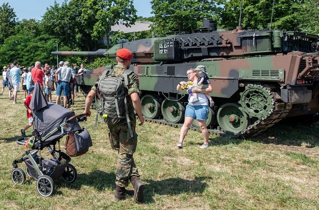 Wie könnte eine linke Wehrhaftigkeit aussehen? Soldat mit Kampfpanzer Leopard 2 und Kinderwagen beim "Tag der Bundeswehr".