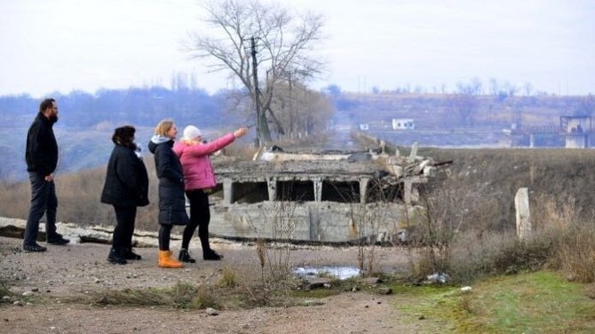 Region Donezk: Ein Hilfsteam aus Arzt, Projektleiterin, Amica-Projektreferentin und Verwaltungsassistentin steht vor einer zerbombten Brücke. Fotos: Amica