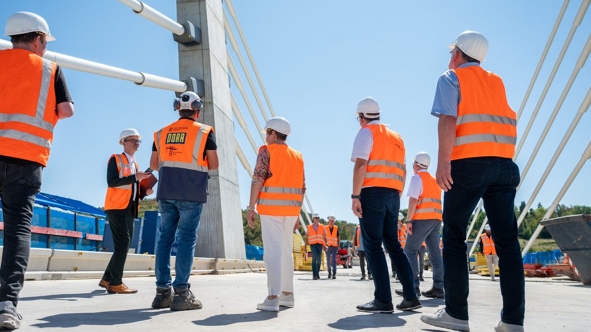 Oben auf der Brücke lässt die Ministerin (Mitte) sich den Brückenbau erklären.