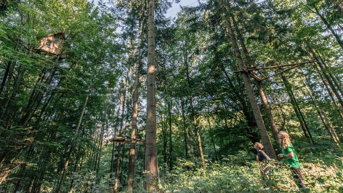 Die Klimaaktivist:innen Charlie Kiehne (links) und Samuel Bosch vor ihrem Baumhaus im Altdorfer Wald, das sie seit über einem Jahr bewohnen.