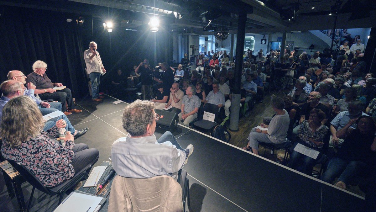 Die Suche nach Wegen zum Frieden im proppenvollen Merlin wurde begrüßt von Josef-Otto Freudenreich (am Mikro). Fotos: Joachim E. Röttgers