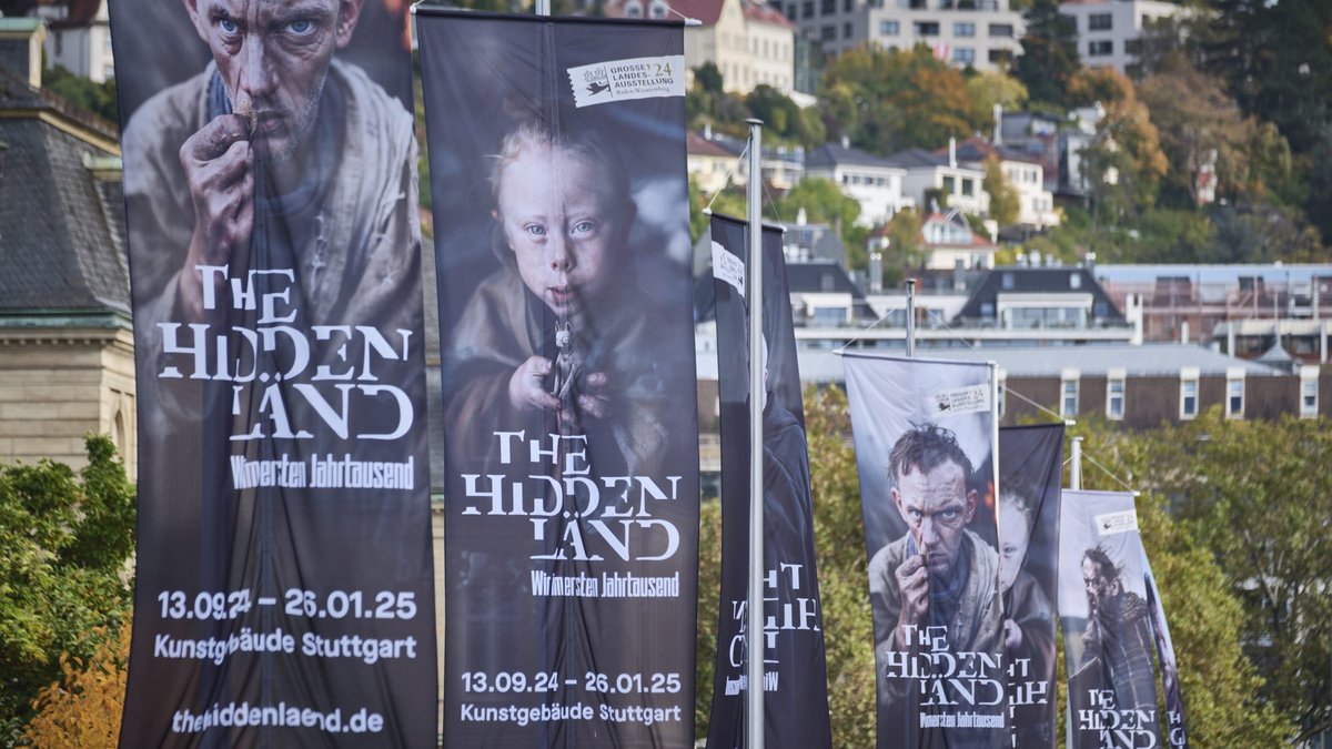 Auf dem Stuttgarter Schlossplatz werben Fahnen für "THE hidden LÄND", darauf KI-generierte Gesichter. Foto: Joachim E. Röttgers Auf dem Stuttgarter Schlossplatz werben Fahnen für "THE hidden LÄND", darauf KI-generierte Gesichter. Foto: Joachim E. Röttgers
