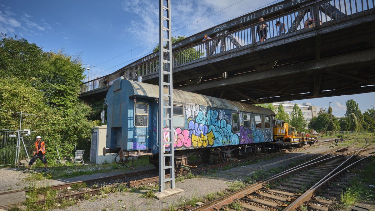 Urmel schiebt den Waggon auf den Platz, Zaungäste gucken.