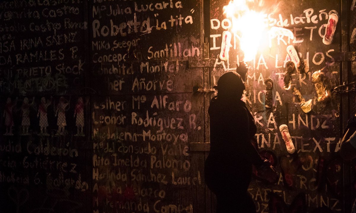Die Namen von Femizid-Opfern stehen auf den Barrikaden, blutige Binden stehen in Flammen.
