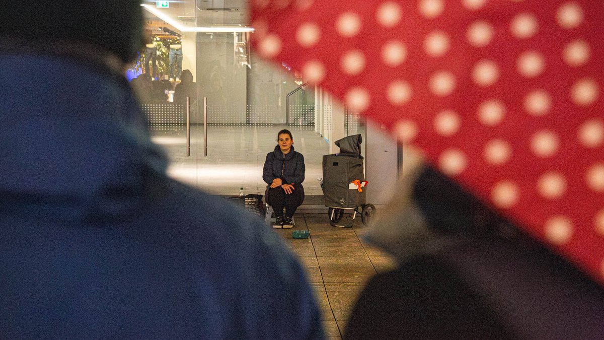 Wie fühlt sich Betteln an? Sie probiert's aus und sitzt immerhin im Trockenen. Mehr Fotos mit Klick auf den Pfeil.