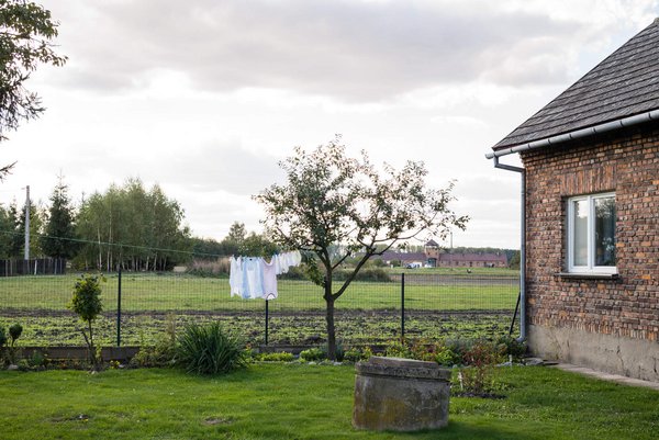 Haus und Garten von Emilia Kramarczyk, im Hintergrund das Lagergelände Auschwitz II/Birkenau. Haus und Garten von Emilia Kramarczyk, im Hintergrund das Lagergelände Auschwitz II/Birkenau.
