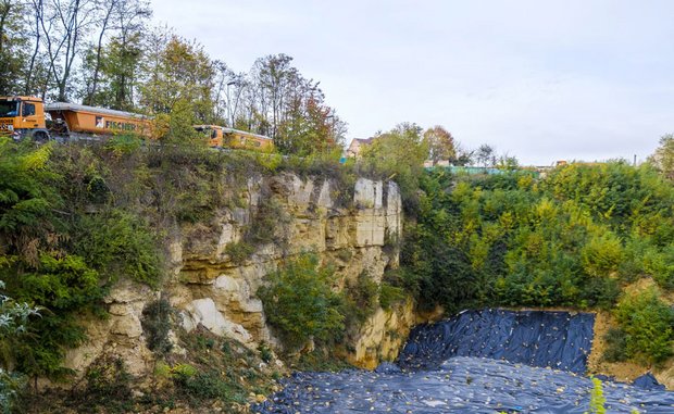 Alle paar Minuten fährt ein Kipplaster an der Steinbruchkante vorbei. Rechts unten ist Folie ausgelegt, damit sich keine Tiere auf dem Gelände ansiedeln.