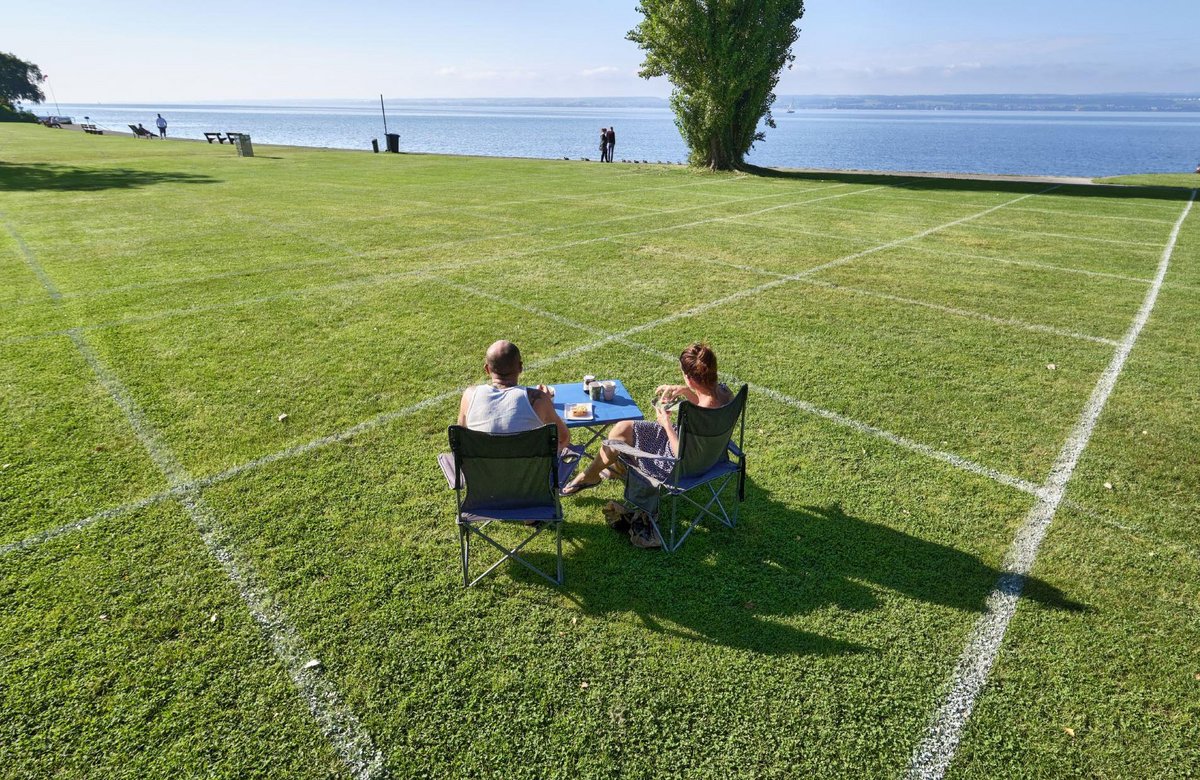Weiße Linien sorgen für Corona-gerechten Abstand auf einer Liegewiese in Meersburg am Bodensee. Das Paar aus Cottbus sitzt jeden Morgen im gleichen Viereck.  