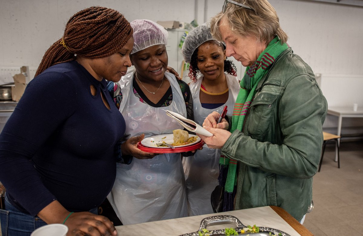In der Landeserstaufnahmestelle Ellwangen: Die Köchinnen Adisa aus Ghana, Abibaz und Julie aus Nigeria (von links) erklären Kontext-Autorin Gesa von Leesen (rechts) das nigerianische Essen.