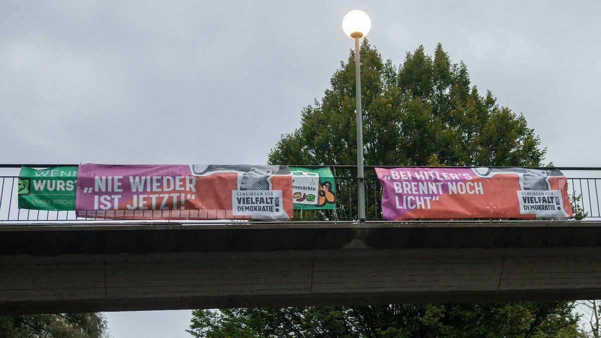 Banner des Demokratie-Bündnisses hängen an Bauzäunen und Geländern in Ulm, wie hier an der Brücke über der Wielandstraße.