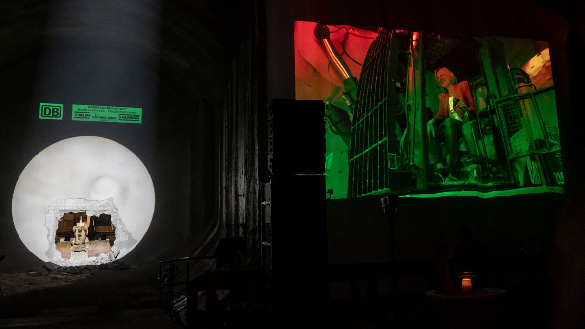 Rechts: die Projektion der Tunnelpatin Arina Freitag. Links: der Durchstich, Anlass für diese Versammlung