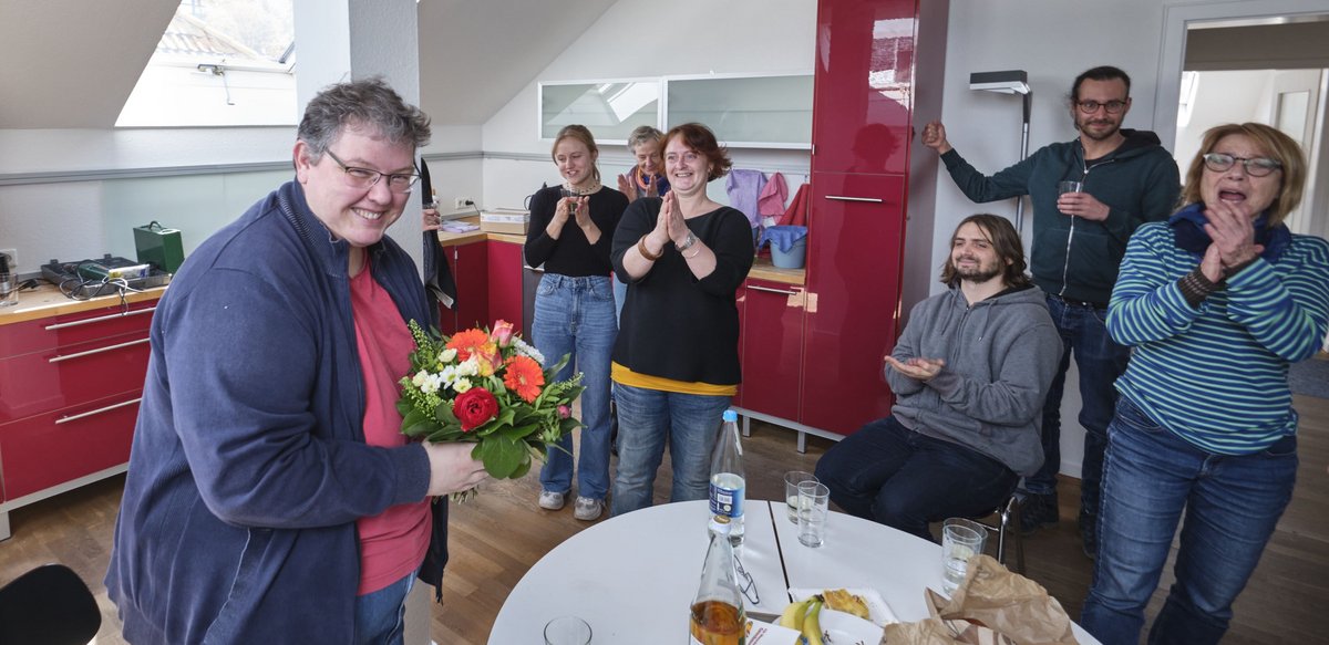 Die Kontext-Redaktion, hier in ihrer neuen Küche, applaudiert für Sibylle Wais (mit Blumenstrauß).