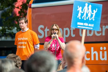 Hedwig Freifrau von Beverfoerde kämpft mit zwei Mikros gegen lustig-laute BürgerInnen-Chöre.