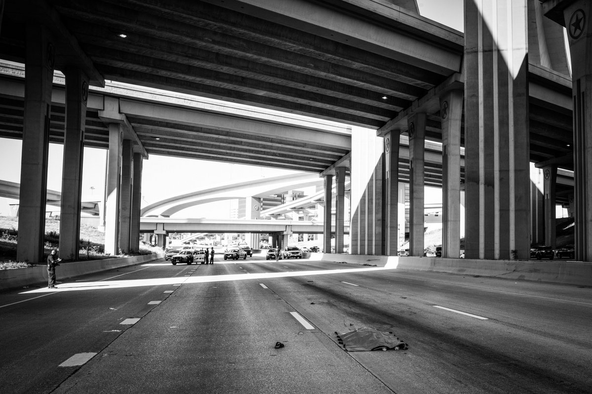 Eine Frau wird mit Plastik abgedeckt, nachdem sie sich während des Berufsverkehrs von einer der erhöhten Schnellstraßen in den Verkehr gestürzt hat. Dallas, Texas, Juni 2022.