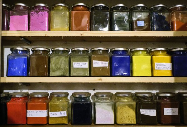 Im Regal stehen Farben, die Schneider von seinen Reisen mitgebracht hat. 