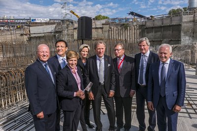 Verspätung hin oder her: Bei der Grundsteinlegung wird fröhlich gelächelt.
