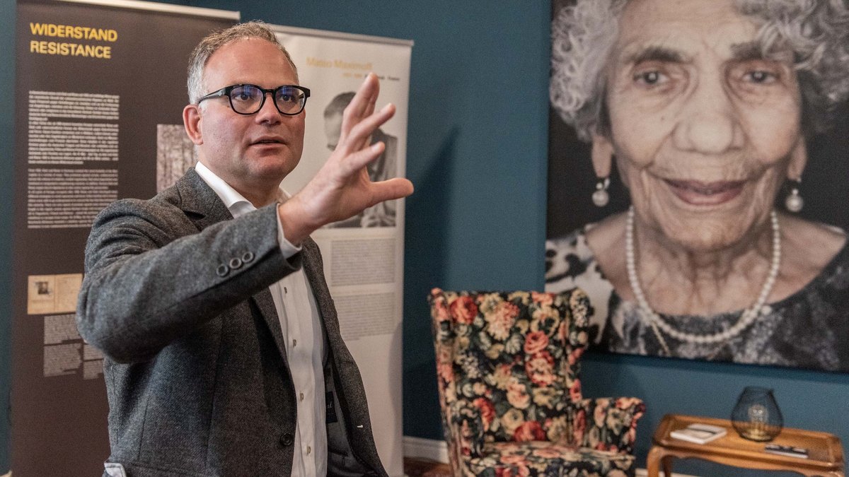 Romno-Kher-Leiter Tim Müller vor dem Portrait der NS-Zeitzeugin Zilly Schmidt.