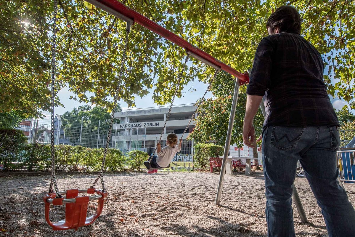 Am Rand des Parkhauses gibt es jetzt einen Spielplatz, auf dem sich Kinder und Eltern beim Schaukeln vergnügen ...