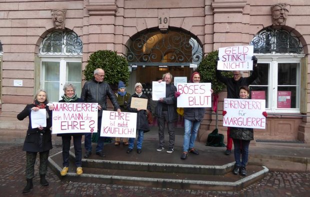 Schlachtruf "Ehrensperre für Marguerre": Kritische Bürger:innen (Dierk Helmken mit dem Plakat "Geld stinkt nicht") vor dem Heidelberger Rathaus. Foto: privat