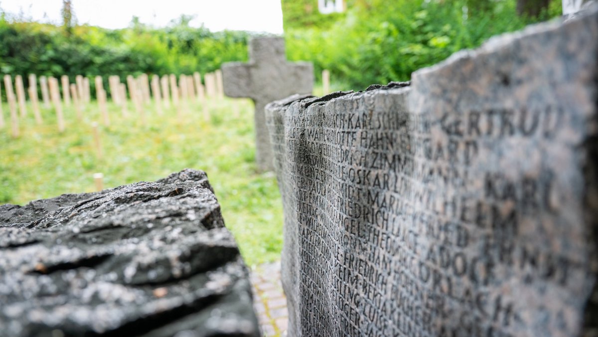Das Steinkreuz und die drei Steinquader mit den 330 Namen darauf, ergänzt um 70 Namen auf 70 Stelen aus Holz. Das Steinkreuz und die drei Steinquader mit den 330 Namen darauf, ergänzt um 70 Namen auf 70 Stelen aus Holz.