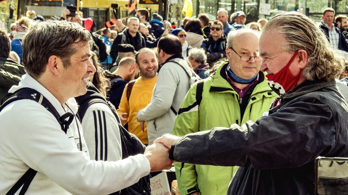 "Querdenken"-Initiator Michael Ballweg beim Handschlag mit dem Ex-AfDler Heinrich Fiechtner (rechtsaußen), dessen Maske stark an ein bekanntes Nazi-Symbol erinnert. Foto: Martin Storz 