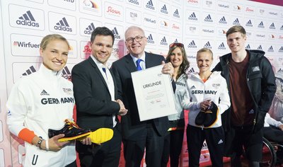Michael Vesper überreicht Berner die Urkunde, welche Sioux als offiziellen Schuhausstatter der deutschen Olympiamannschaft auszeichnet. Foto: Sioux