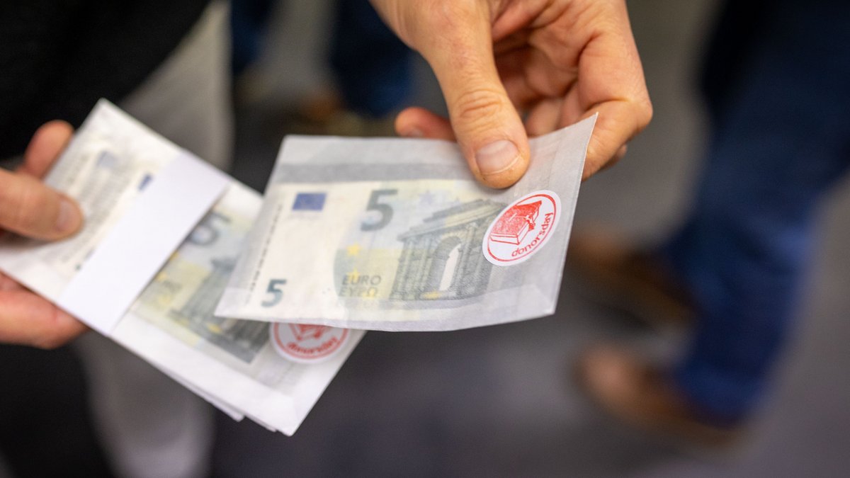 Am Eingang bekommen die Ausstellungsbesucher:innen Geld – zum Weiterverteilen. Fotos: Julian Rettig