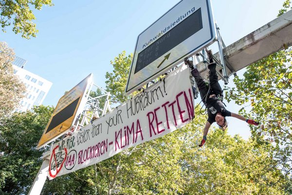 Welt steht Kopf: Kletteraktivistin Lecomte beim Protest gegen die IAA in Frankfurt am Main.