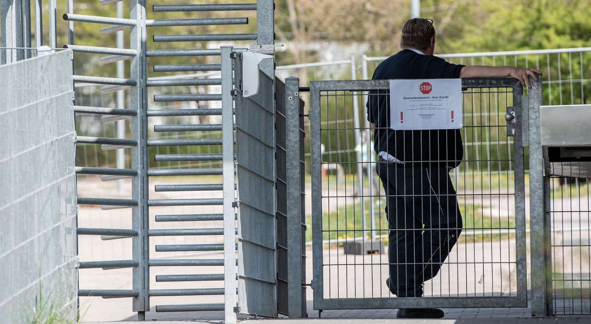 Am Tor zur LEA ein Wachmann, maskenfrei. "Quarantänebereich", steht auf dem Schild. Mehr Zäune mit Klick auf den Pfeil. Fotos: Jens Volle