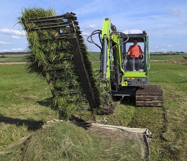 Eigenkonstruktion mit Fahrwerk aus Holzbalken, die eine Matte zum Abtransport des Mähguts hinter sich herzieht. Foto: Rainer Lang