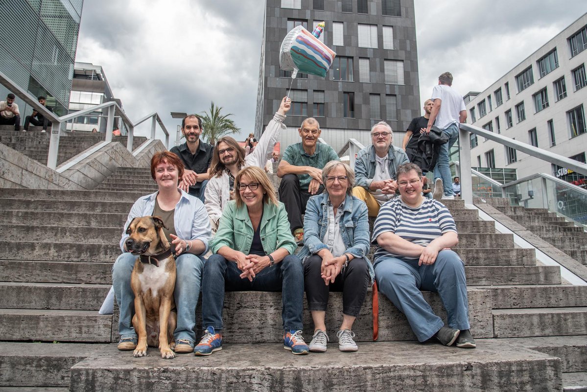 Die Kontext-Redaktion auf der legendären Stuttgarter Krawalltreppe: (von links) Anna Hunger, Oliver Stenzel, Minh Schredle mit Geburtstagstorte, Susanne Stiefel, Joachim E. Röttgers, Gesa von Leesen, Josef-Otto Freudenreich, Sibylle Wais. Foto: Jens Volle