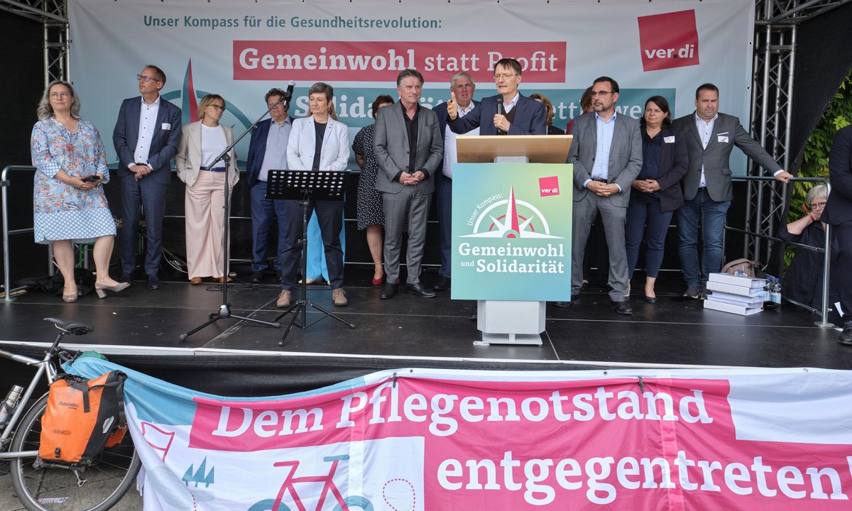 Im Trockenen und auf der Bühne: die Gesundheitsminister:innen der Länder mit Bundesgesundheitsminister Karl Lauterbach am Rednerpult.